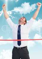 Businessman crossing finish line with arms up against sky and cloud