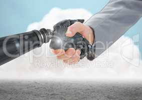 Close-up of businessman shaking hands with robot hand with clouds in background