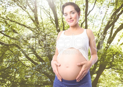 Portrait of pregnant woman standing against greenery