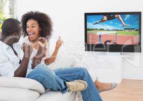 Couple cheering while watching hurdle race on television