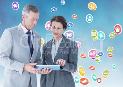 Businesspeople using digital tablet against multiple icons background