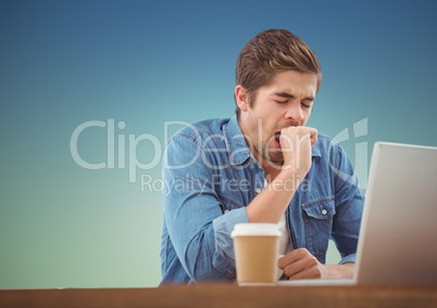 Sleepy man yawning while working on laptop