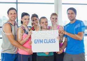 Portrait of group of happy people holding blank placard in gym