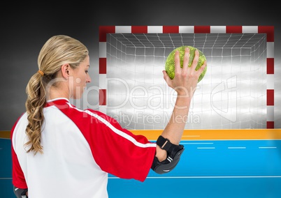 Female athlete throwing handball against goal post in background