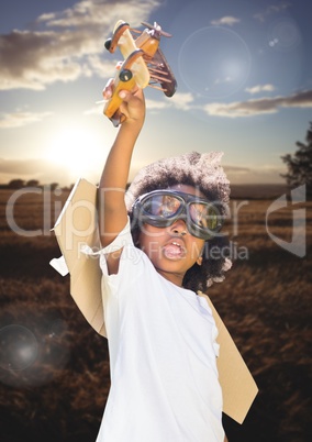 Kid pretending to be a pilot in field at sunset