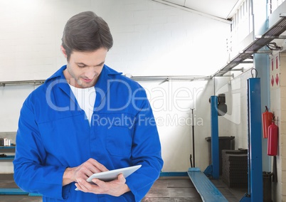 Mechanic using digital tablet against garage in background