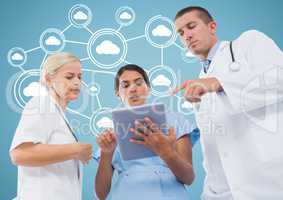 Male and female doctors discussing over digital tablet with cloud computing icons in background