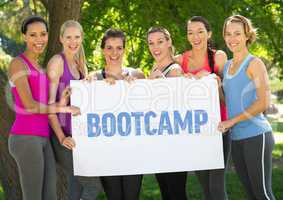 Fitness women hold placard with text boot camp in the park