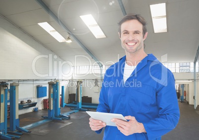 Smiling mechanic holding digital tablet in garage
