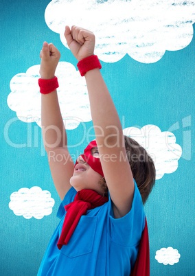 Boy in superhero costume pretending to fly against clouds in background