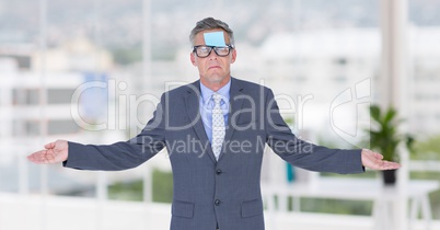 Businessman with arms stretched and sticky note stuck on forehead