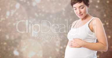 Pregnant woman touching her belly against defocused background