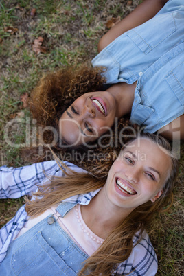 Female friends lying together on grass in park