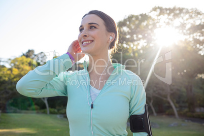 Smiling female jogger with headphones taking a break from exercise