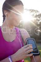 Smiling female jogger listening to music on mobile phone