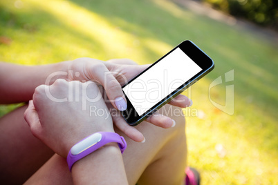 Woman with fitness band on her wrist using her mobile phone