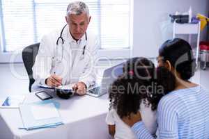 Doctor writing on clipboard while consulting patient