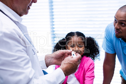 Girl smiling while doctor checking temperature on thermometer