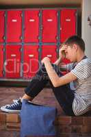 Sad schoolboy sitting on staircase