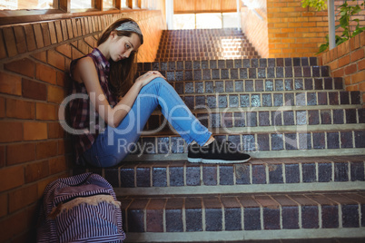 Sad schoolgirl sitting alone on staircase