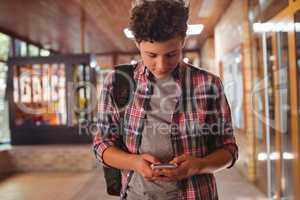 Schoolboy using mobile phone in corridor at school