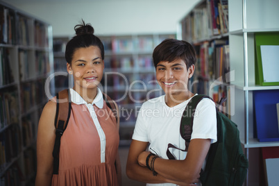 Portrait of school kids standing with arms crossed in library