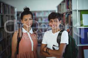 Portrait of school kids standing with arms crossed in library