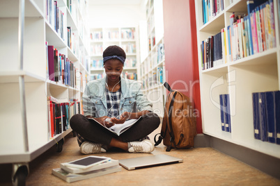 Schoolgirl listening music on headphones in library