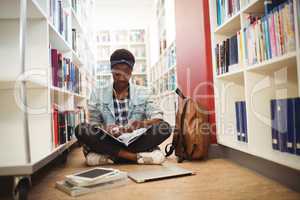 Schoolgirl listening music on headphones in library