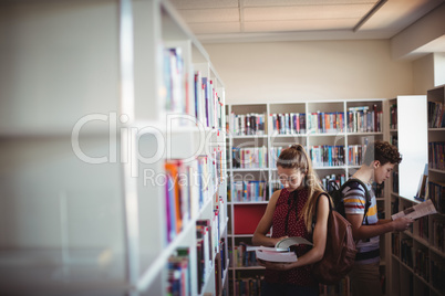 Attentive classmates reading book in library