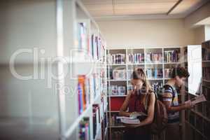 Attentive classmates reading book in library