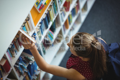 High angle view of schoolgirl selecting book from bookshelf in library