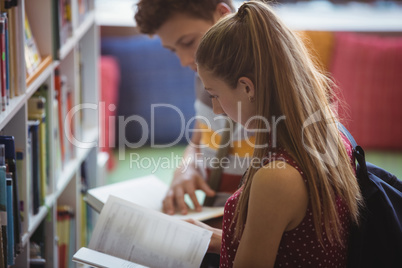 Attentive classmates reading book in library