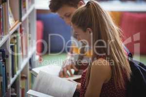 Attentive classmates reading book in library