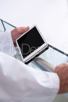 Doctor using a digital tablet in the passageway at hospital