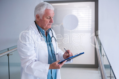 Doctor writing on clipboard in the passageway