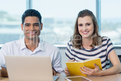 Portrait of smiling business colleagues using laptop at desk