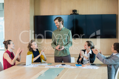 Business team applauding their colleague in conference room