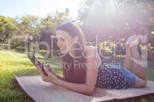 Smiling woman lying on mat and using digital tablet