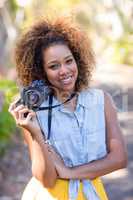 Smiling woman standing with digital camera