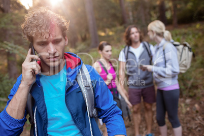 Young man talking on the phone while hiking with his friends