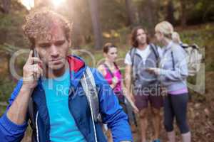 Young man talking on the phone while hiking with his friends