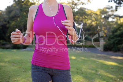 Mid section of female jogger listening to music while jogging