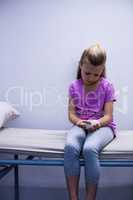 Girl with injured hand sitting on stretcher bed