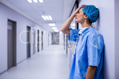 Sad surgeon leaning on wall in corridor