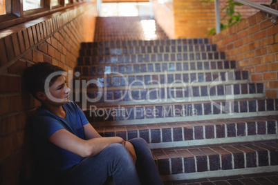 Sad schoolboy sitting alone on staircase