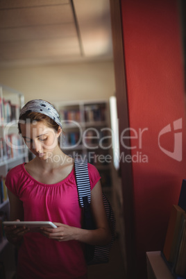 Attentive schoolgirl using digital tablet in library