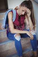 Sad schoolgirl sitting alone on staircase