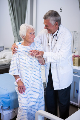 Doctor assisting senior patient in ward