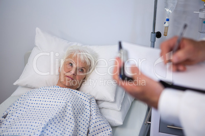 Doctor writing medical details of a senior patient